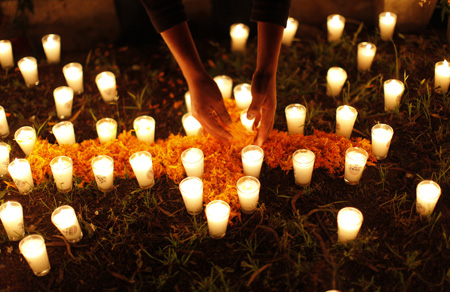 A man puts flower petals on the grave of a baby at the cemetery in Tzintzuntzan, Mexico October 31, 2009. 