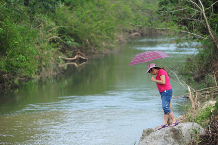 A woman searches for the fled crocodiles along a brook contiguous to the reservoir of the crocodile-breeding aquafarm in Huangshan Reservoir, Changfeng Township, Wanning City, south China's Hainan Province, Oct. 31, 2009. (Xinhua/Meng Zhongde)