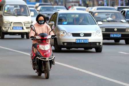 A woman wearing a facial mask and cold weather clothing rides a motorcycle in a street of Zhengzhou, capital of central China's Henan Province, Nov. 2, 2009.(Xinhua/Wang Song)