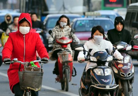 Local citizens wearing facial masks and cold weather clothing make their way in a street of Zhengzhou, capital of central China's Henan Province, Nov. 2, 2009.(Xinhua/Wang Song)