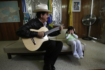 Honduras' ousted President Manuel Zelaya plays the guitar next his granddaughter Irene Melara during a visit inside the Brazilian embassy in Tegucigalpa, November 1, 2009. (Xinhua/Reuters Photo)