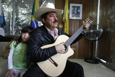 Honduras' ousted President Manuel Zelaya plays the guitar next to his granddaughter Irene Melara during her visit inside the Brazilian embassy in Tegucigalpa, November 1, 2009. (Xinhua/Reuters Photo)