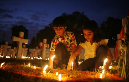 Children light candles as they offered prayers for departed loved ones to mark All Souls' Day at the cemetery of Holy Rosary church in Dhaka November 2, 2009.