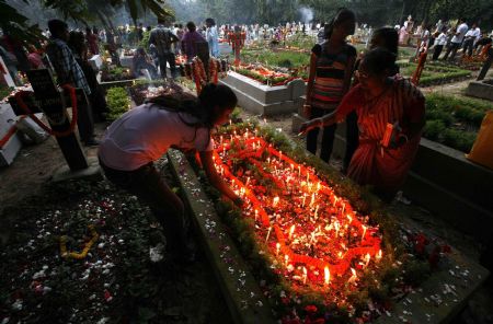 Christians offer prayers beside a grave of their relative at a cemetery during the observance of All Souls' Day in the eastern Indian city of Kolkata November 2, 2009.