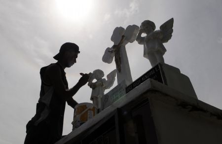 A Salvadoran paints a sculpture at a grave during the Day of the Dead at a cemetery in Cuscatlan 45km (28 miles) north of San Salvador November 2, 2009. Salvadoran Catholic faithfuls mark every November 2, the Day of the Dead, by remembering their deceased relatives.