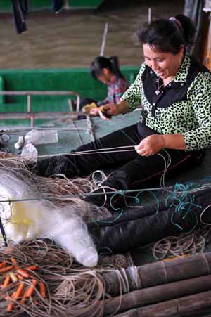 Fishermen repair fishing net in a port in Haikou, capital of south China's Hainan Province, Nov. 2, 2009.[Guo Cheng/Xinhua]