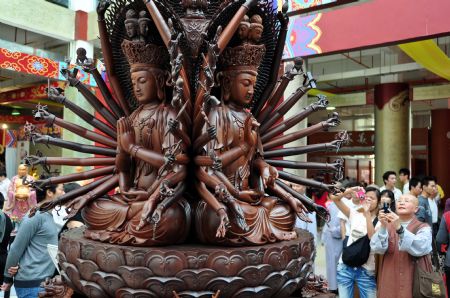 Visitors take photos of an wooden sculpture work on the Buddhism Expo held in Putian, southeast China's Fujian Province, Nov. 2, 2009. The four-day-long China Putian Buddhism Expo kicked off here on Monday with nearly 10,000 exhibits on shown. (Xinhua/ Lin Jianbing)