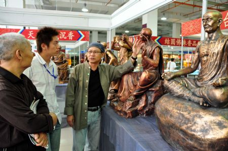 An artist (R) from southeast China's Taiwan Province shows his copper sculpture work on the Buddhism Expo held in Putian, southeast China's Fujian Province, Nov. 2, 2009. The four-day-long China Putian Buddhism Expo kicked off here on Monday with nearly 10,000 exhibits on show.[Photo by Lin Jianbing]
