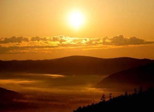 The sun rises from behind the mountains.