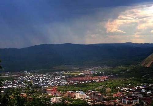 The sleepy village is bathed in sunrays breaking through the morning clouds.