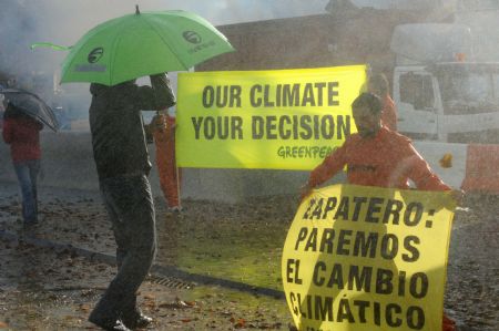 A Greenpeace activist displays a banner during a demonstration outside the venue of the UN 2009 5th Climate Change Talks in Barcelona, Spain, Nov. 5, 2009.(Xinhua/Chen Haitong)