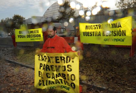 A Greenpeace activist displays a banner during a demonstration outside the venue of the UN 2009 5th Climate Change Talks in Barcelona, Spain, Nov. 5, 2009.(Xinhua/Chen Haitong)