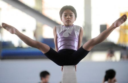 Yang Le, a 6-year-old girl, practises on the balance beam in a gymnastics school of Xiantao, city of central China