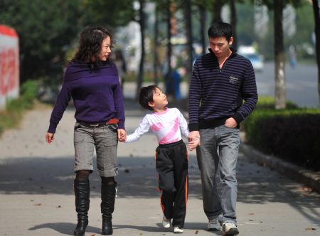 Yang Le (C), a 6-year-old gymnast, walks on the street, led by her parents in Xiantao, city of central China