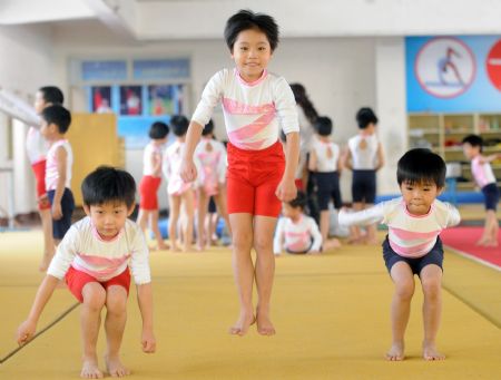 Yang Le (C), a 6-year-old girl, togher with her little teammates practise basic gymnastics skills in a gymnastics school of Xiantao, city of central China's Hubei Province, on Oct. 15, 2009.(Xinhua/Li Xiaoguo)
