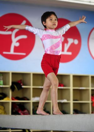 Yang Le, a 6-year-old girl, practises on the balance beam in a gymnastics school of Xiantao, city of central China's Hubei Province, on Oct. 15, 2009.(Xinhua/Hao Tongqian)