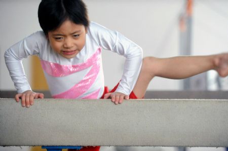 Yang Le, a 6-year-old girl, climbs the balance beam in a gymnastics school of Xiantao, city of central China's Hubei Province, on Oct. 15, 2009.(Xinhua/Li Xiaoguo)
