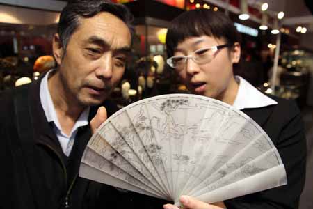 A staff worker shows a jade fan on a jewelry exhibition held at China International Exhibition Center in Beijing, China, Nov. 5, 2009. The 5-day-long 2009 China International Jewelry Exhibition kicked off here on Thursday with about 600 companies from 15 countries and regions on shown. (Xinhua)