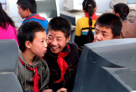 Liu Lei (C, front) gets excited after typing his name on the computer for the first time at Jinfengliangtian Primary School in Yinchuan, northwest China's Ningxia Hui Autonomous Region, in the file photo taken on Oct. 18, 2006, the day the Hope cyber school of Jinfengliangtian Primary School opened. (Xinhua Photo)