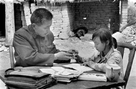 Hu Zunxun (L), a teacher of Jinzhai County Hope Primary School, tutors his student Hu Yali to make up the lessons she had missed in Jinzhai County, east China's Anhui Province, in this file photo taken on May, 1991. Hu Zunxun travel over 10 kilometers to help Hu Yali as she had discontinued her study for one year. (Xinhua Photo)