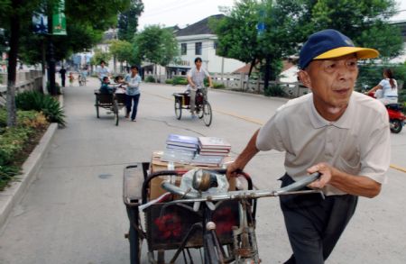 Zhou Huosheng, a 73-year-old retired teacher, sells books with a tricycle in Qiandeng town, Kunshan city, east China's Jiangsu Province, in this photo taken on Sept. 7, 2006. Zhou Huosheng has been using his savings and income raised by selling books to help the dropouts in the mountainous area since 1994.(Xinhua Photo)