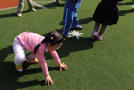 Song Xinyi helps herself up after falling down on the ground in her kindergarten in Chengdu, capital city of southwest China