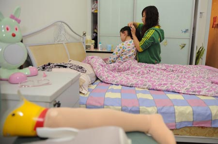 Song Xinyi (L) sits on her bed as the girl friend of her uncle undoes her hair in Chengdu, capital city of southwest China's Sichuan Province, on Oct. 27, 2009. 