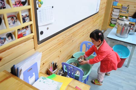 Song Xinyi puts back the dishes in her kindergarten in Chengdu, capital city of southwest China's Sichuan Province, on Oct. 26, 2009. 