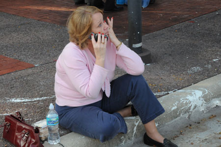 A survivor calls her family by cell phone outside the Gateway Center building where a shooting spree took place in downtown Orlando, Florida, the U.S., Nov. 6, 2009. A gunman on Friday opened fire inside the Gateway Center building, killing at least one person and wounding at least five others. (Xinhua/Zhou Xiaozheng)