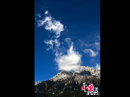 Soaring to 5500m, some 35km from Lijiang, is Yulong Xueshan, also known as Mt Satseto. In Lijiang City you can have a magnificent view of Jade Dragon Snow Mountain, with the main peak thrust into the clouds, the Old Man Peak standing out on the right and Black Snow Peak on its left. The 13 peaks of 18,360-foot Jade Dragon Snow Mountain, a treasure of wild plants and rare animals, are like a silver dragon lying in the clouds. Awesome and unconquered, they dominate the Lijiang Plain. [[Photo by Sarah] 