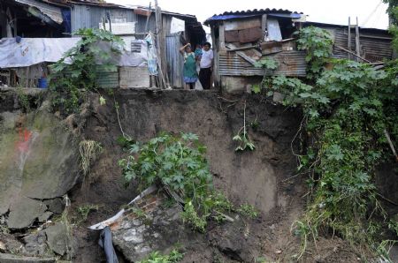 Salvadorans look at their houses that were damaged by heavy rains in San Salvador November 8, 2009.[Xinhua/Reuters]