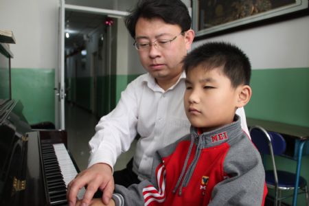 Liu Hao, an eight-year-old blind boy of a worker's family, learns playing piano with his teacher Liu Yongxue, in Chifeng City, north China's Inner Mongolia Autonomous Region, Nov. 3, 2009. [Xinhua]