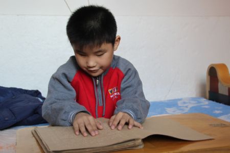 Liu Hao, an eight-year-old blind boy of a worker's family, learns the Braille by himself at home, in Chifeng City, north China's Inner Mongolia Autonomous Region, Nov. 3, 2009. [Xinhua]