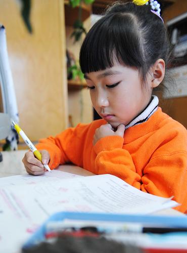 Zhang Mingyang does her homework after her morning exercise of skating in a weekend in Harbin, capital of northeast China's Heilongjiang province, Nov. 1, 2009.[Xinhua]