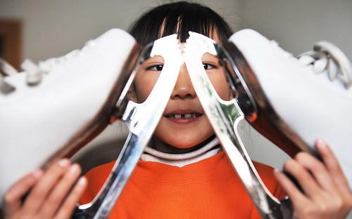 Zhang Mingyang poses for photos with her skates at home in Harbin, capital of northeast China's Heilongjiang province, Nov. 1, 2009.[Xinhua]