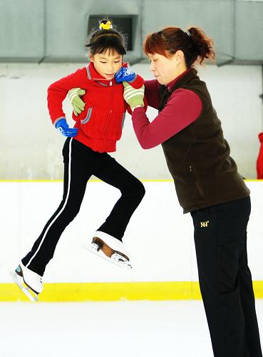 Zhang Mingyang (L) trains on the ice with her teacher's help in Harbin, capital of northeast China's Heilongjiang province, Nov. 1, 2009. [Xinhua]