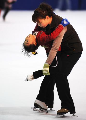 Zhang Mingyang (L) skates with her teacher's help during evening exercises in Harbin, capital of northeast China's Heilongjiang province, Oct. 30, 2009.[Xinhua]