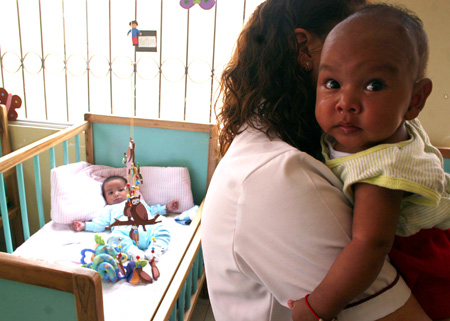 A nursery teacher takes care of kids at the kindergarten of a women's prison in Quito, Ecuador, Nov. 6, 2009. [Hao Yunfu/Xinhua]