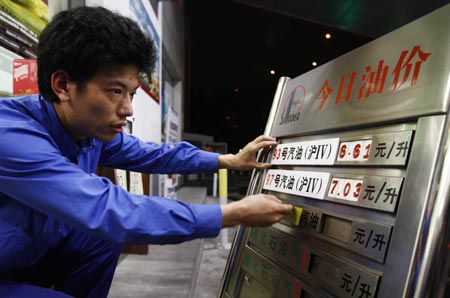 A worker adjusts the price tag at a gas station in east China's Shanghai Municipality, early Nov. 10, 2009. China raised gasoline and diesel prices both by 480 RMB yuan (US$70.28) per tonne on Nov. 10. [Xinhua]