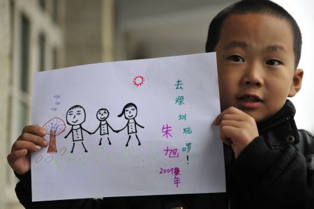 Zhu Xu shows his drawing which depicts his summer holidays with his parents, in Xianfeng county in Enshi, Central China's Hubei province, October, 12, 2009. [Xinhua]