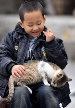 Zhu Xu plays with a cat at home in Enshi Central China's Hubei province, October, 11, 2009. [Xinhua]