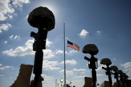 The boots, helmets and rifles of the slain soldiers are placed behind each of their service photographs on November 10, 2009 at the Fort Hood Army base, Texas, to honor 13 people killed by a U.S. Army psychiatrist. [Xinhua] 