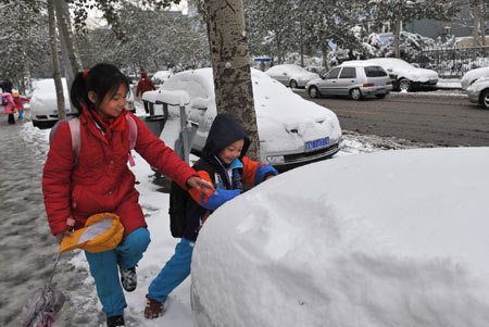 Two pupils play with snow in Beijing, capital of China, Nov. 10, 2009. Beijing witnessed the second snowfall this winter on Nov. 10. Heavy snow blanketed Beijing and other parts of north China Tuesday, causing air travel delays and highway closures. [Xinhua]