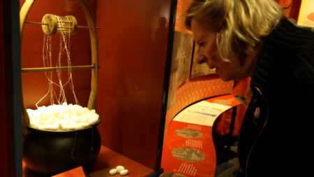 A woman views a silkworm cocoon reeling machine during the media preview of the 'Travelling the Silk Road' exhibition at the American Museum of Natural History in New York Nov. 10, 2009.[Xinhua]