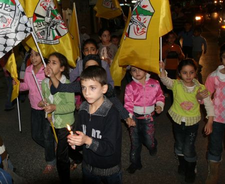 Palestinian kids hold flags and candles during a candle-lighting ceremony marking the fifth anniversary of late Palestinian leader Yasser Arafat's death in the West Bank town Qalqilya, Nov. 10, 2009. Yasser Arafat passed away in Paris on Nov. 11, 2004. [Xinhua]