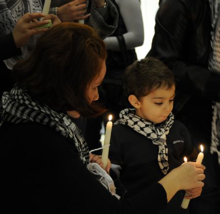 A Palestinian woman helps her son light candles at the grave of the late Palestinian leader Yasser Arafat during a vigil marking the fifth anniversary of Arafat's death in the West Bank city of Ramallah, Nov. 10, 2009.[Xinhua]