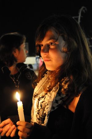 A Palestinian girl holds a candle at the grave of the late Palestinian leader Yasser Arafat during a vigil marking the fifth anniversary of Arafat's death in the West Bank city of Ramallah, Nov. 10, 2009.[Xinhua]