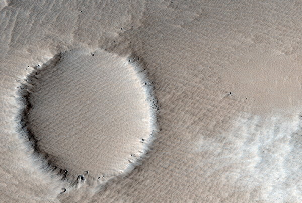 A small crater partially buried in wind-blown ejecta from a much larger crater. These spectacular images from the red planet show the amazing landscape on the surface of our nearest planet. The scalloped sand dunes and giant craters, rocky outcrops and deep gullies have all been taken by a NASA Mars Reconnaissance Orbiter satellite orbiting the fireball planet Mars 187 miles above its surface. [CFP]