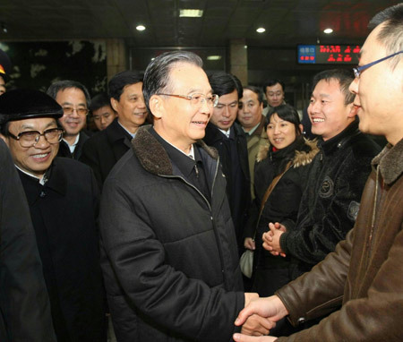 Chinese Premier Wen Jiabao (C, front) shakes hands with a passenger in the waiting room of the railway station in Shijiazhuang, capital of north China&apos;s Hebei Province, Nov. 12, 2009. Chinese Premier Wen Jiabao went to snow-ravaged Shijiazhuang on Thursday afternoon to oversee relief work. [Liu Weibing/Xinhua]