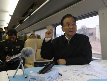 Chinese Premier Wen Jiabao (R) speaks during a meeting held on the train as he travels to Shijiazhuang, capital of north China&apos;s Hebei Province, Nov. 12, 2009. Chinese Premier Wen Jiabao went to snow-ravaged Shijiazhuang on Thursday afternoon to oversee relief work. [Liu Weibing/Xinhua]